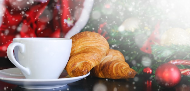 Banner de café de navidad. taza de cristal blanco capuchino caliente con croissants y copyspace