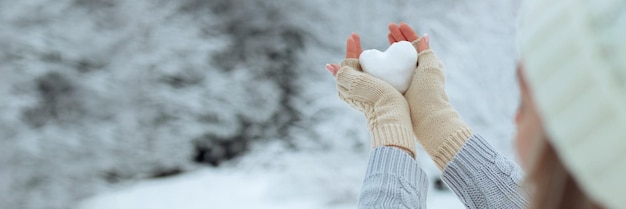 Foto banner closeup schneeherz in händen in strickhandschuhen auf dem hintergrund der schneedecke valentine39s day