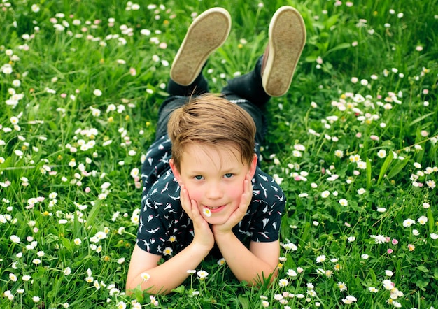 Banner com cara de criança de primavera menino de primavera criança feliz infância sorridente deitado na grama conceito de sonho