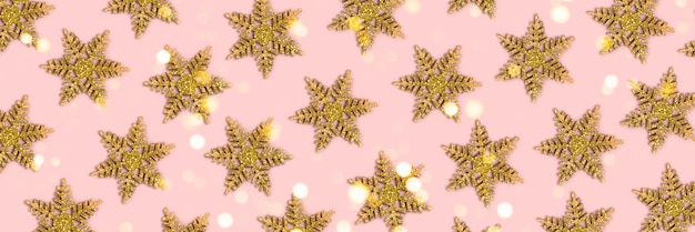 Banner com padrão de flocos de neve dourados em um fundo rosa com bokeh brilhante