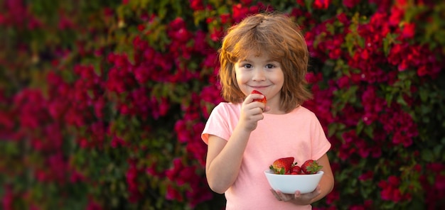 Banner com retrato de crianças de primavera criança feliz come morangos no verão ao ar livre