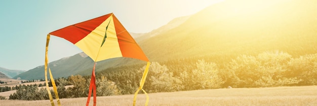 Banner con cometa triangular se eleva hacia el cielo sobre colinas Tonos de enfoque suave