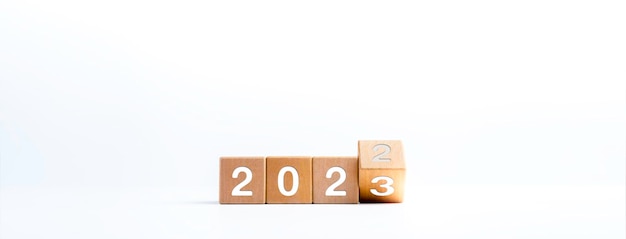 Banner de concepto de feliz año nuevo 2023 Voltear el calendario de números de año 2022 a 2023 en bloques de cubo de madera aislados en fondo blanco para el cambio de año nuevo para comenzar cosas nuevas o nuevos negocios