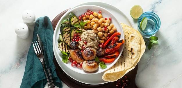 Banner da tigela de Buda mediterrânea italiana com cebola caramelizada Baba ghanoush, grão de bico picante e legumes grelhados, comida vegana saudável e pão pita