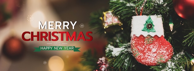 Banner de feliz Natal e feliz ano novo para a capa ou capa do site de mídia social ou decoração de página de fã. Foto de ornamentos decorativos com texto de bênção de Natal e letras com meia vermelha e bokeh.