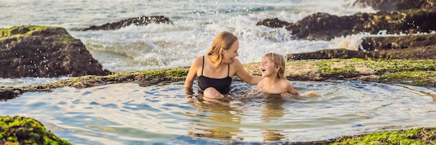 Banner de formato longo mãe e filho turistas na praia de pantai tegal wangi sentado em um banho de mar