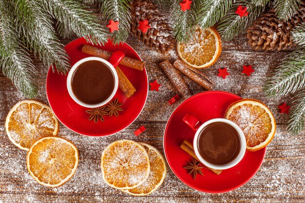 Banner de Natal com árvore verde, cones, copos vermelhos com chocolate quente, laranja e canela.