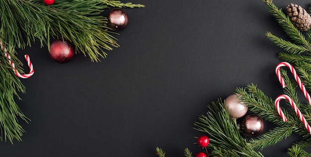 Banner de Natal feito de decoração e galhos de árvores de natal em fundo preto saudação de ano novo