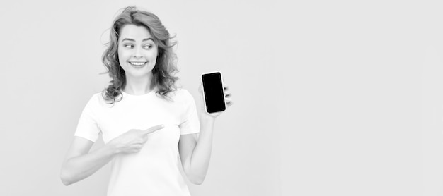 Banner de retrato de rosto isolado de mulher com espaço de cópia simulado animado jovem isolado fundo amarelo usando telefone celular mostrando gesto okey