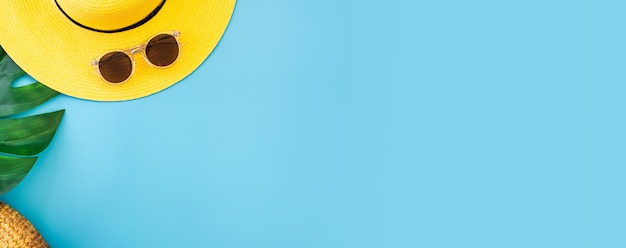 Banner de verão azul com chapéu amarelo, óculos escuros e folha de monstera em azul