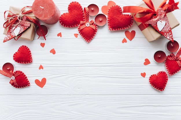 Banner para el día de San Valentín con corazones decorativos, velas y regalos en un fondo de madera blanca