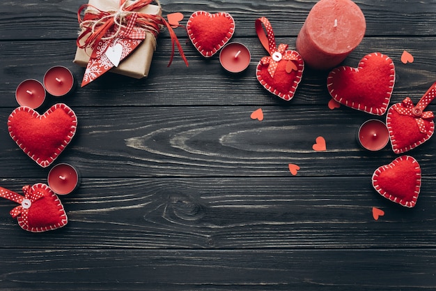 Banner para el día de San Valentín con corazones decorativos, velas y regalos en un fondo de madera oscura