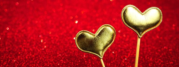 Banner del Día de San Valentín con dos corazones en un fondo rojo bokeh. Diseño de celebración de brillo brillante. Amor y decoración romántica para el 14 de febrero