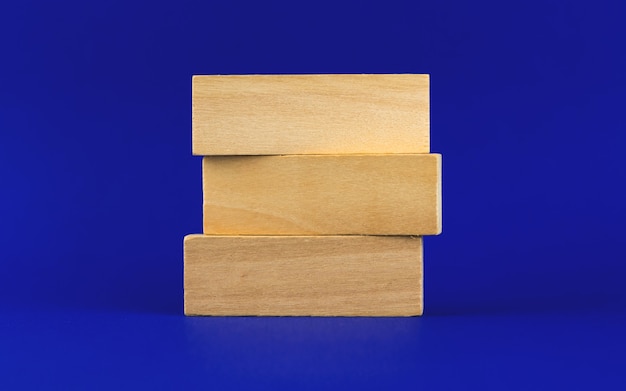 Banner de estrategia empresarial o plantilla con tres clavijas de madera, bloques sobre un fondo azul, lugar para su foto de texto