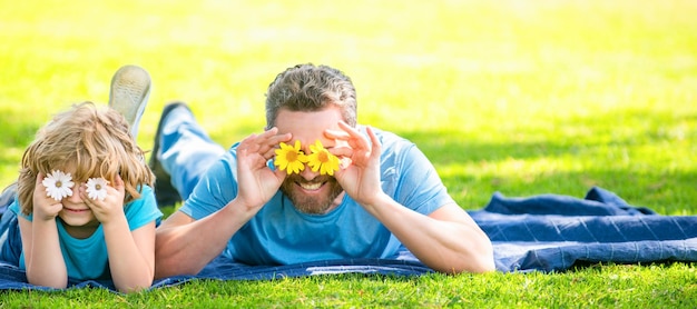 Banner de feliz padre con hijo relajarse juntos en el césped verde del parque divirtiéndose con flores familia feliz