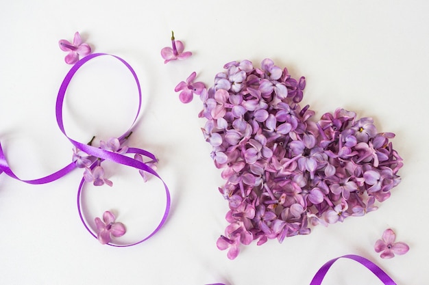 Banner de fondo de tarjeta de felicitación creativa para el 8 de marzo, con flores lilas y cintas sobre un fondo blanco, Día Internacional de la Mujer