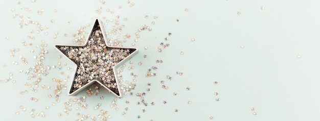 Foto banner hecho de estrella con destellos y formas para pan de jengibre sobre fondo azul pastel navidad