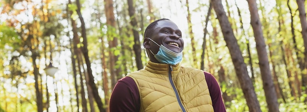 Banner hombre afroamericano con ropa informal quitarse la máscara médica sonriendo feliz caminando en ci