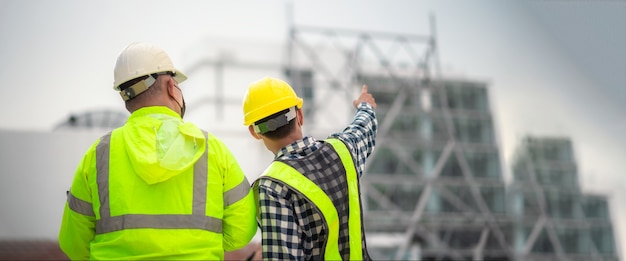 Banner: Ingenieros civiles y constructores civiles inspeccionan la estructura y los planos del sitio de construcción. El ingeniero civil y los constructores civiles inspeccionan el sitio de construcción real. Ingeniero civil inspecciona el edificio.