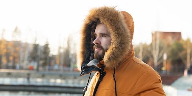 Banner inverno está chegando homem vestindo jaqueta de inverno no fundo do parque frio com espaço de cópia e lugar