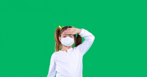 Foto banner langer grüner hintergrund, ein mädchen steht, hält ihre linke hand auf der stirn und trägt eine schutzmaske