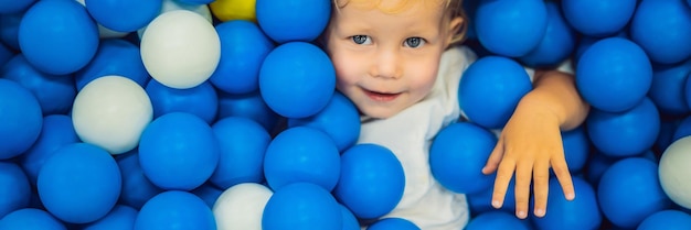 Banner langformatiges Kind, das im Bällebad bunte Spielzeuge für Kinder im Kindergarten oder Vorschulspiel spielt