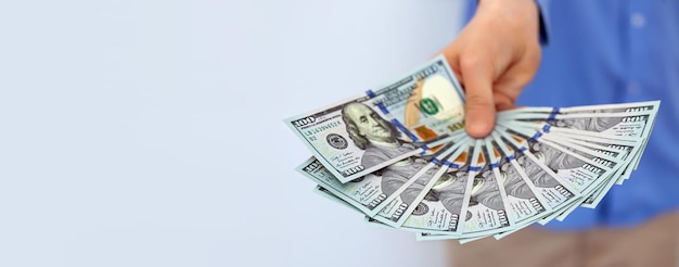 Banner con mano sosteniendo billetes de cien dólares estadounidenses sobre fondo gris Dinero estadounidense