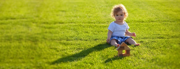 Banner mit Frühlingskindergesichtsversicherung Kinderbabyspiel im grünen Gras warme Frühlingszeit im Park