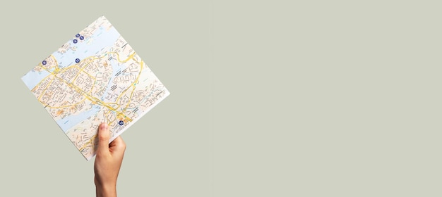 Banner mit handhebender Karte Reiserouten studieren Tourismuskonzept auf grauem Hintergrund Kopierbereich