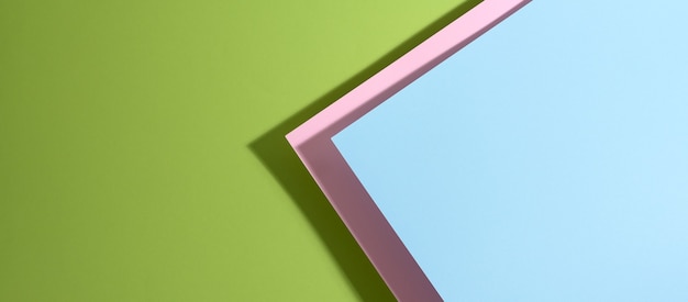 Banner moderno de superfície verde brilhante com folhas de papel azul e rosa com sombra. Pano de fundo abstrato com espaço em branco, postura plana