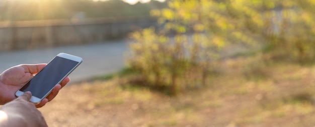 Banner Mujer manos sosteniendo teléfono móvil al aire libre navegando por internet en línea estilo de vida tecnológico. Cerrar la mano de la mujer con el mensaje de texto del gadget del teléfono inteligente panorámica con espacio de copia. Estilo de vida tecnológico