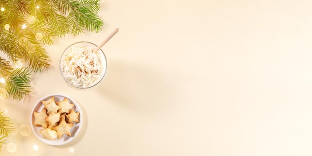 Banner de Navidad con postres navideños, ponche de huevo tradicional y estrellas de galleta de jengibre en beige. Vista superior.