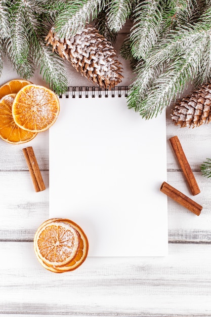 Banner navideño con árbol verde, conos, naranja, canela y cuaderno.