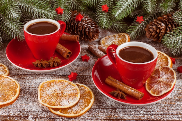 Banner navideño con árbol verde, conos, tazas rojas con chocolate caliente, naranja y canela.