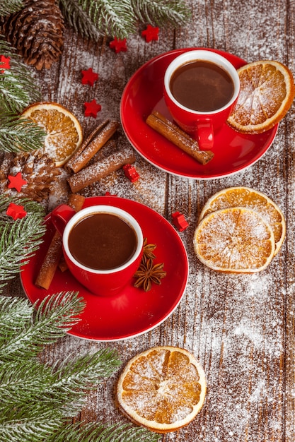 Banner navideño con árbol verde, conos, tazas rojas con chocolate caliente, naranja y canela.