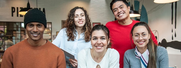 Banner o encabezado horizontal con compañeros de trabajo multiétnicos sonrientes mirando la cámara haciendo una foto del equipo en la sala multifuncional del restaurante de pizza para el brunch de trabajo Grupo de trabajo diverso
