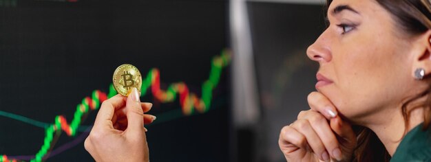 Banner o encabezado horizontal Joven empresaria sosteniendo una representación de bitcoin y mira la moneda pensando en cómo hacer un buen comercio e inversión en línea