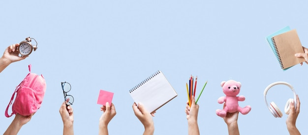 Banner con papelería escolar en manos femeninas sobre fondo azul con espacio de copia Lápices de mochila portátil y otras herramientas sobre fondo de color