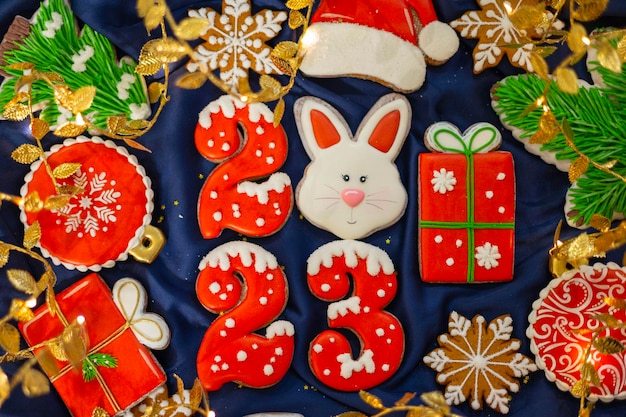 Banner para biscoitos de gengibre de Natal e Ano Novo números 2023 flocos de neve Chapéu de Papai Noel Árvores de Natal guirlandas em tecido de seda azul fundo símbolo de coelho de gengibre Calendário do zodíaco chinês