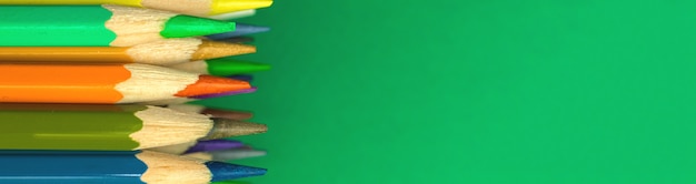 Foto banner plano escolar con lápices de colores y afilados en un escritorio verde, espacio de copia, concepto de útiles escolares, espacio de copia