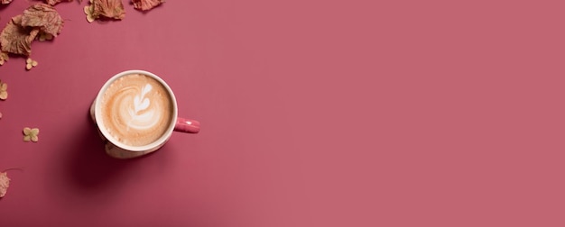 Banner plano de otoño con hojas secas y taza de café con leche sobre fondo de color rosa oscuro Concepto creativo de otoño de acción de gracias otoño espacio de copia de vista superior