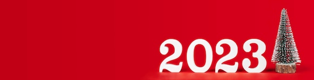 Banner rectangular largo rojo con números de madera blanca 2023 soporte con árbol de Navidad de juguete Espacio de copia Lugar para texto