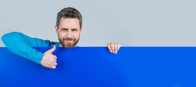 Foto banner de retrato de cara de hombre con espacio de copia hombre alegre detrás de pancarta de papel en blanco con espacio de copia para presentación pulgar arriba comunicación