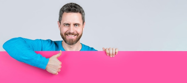 Foto banner de retrato de cara de hombre con espacio de copia hombre feliz detrás de banner de papel en blanco con espacio de copia para oferta de trabajo mostrar propuesta de pulgar hacia arriba