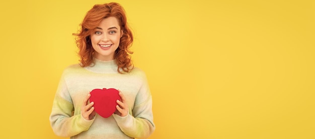 Banner de retrato de cara de mujer aislada con espacio de copia mujer pelirroja feliz con corazón rojo sobre fondo amarillo