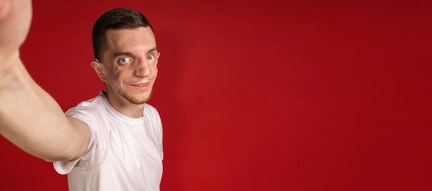 Banner en rojo con un hombre en una camiseta blanca tomando selfies copyspace