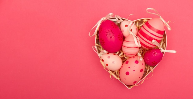 Banner rosa con huevos de Pascua en la caja en forma de corazón