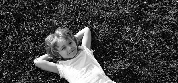 Banner con rostro de niño de primavera niño feliz acostado en el fondo de hierba niño lindo niño niño disfrutando en