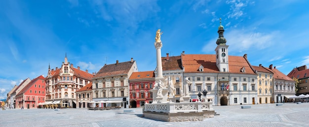 Banner, Stadtzentrum von Maribor in Slowenien. Rathaus und Pestdenkmal auf dem Hauptplatz von Maribor. Blauer Himmel, helles Tageslicht, panoramische Stadtlandschaft. Berühmtes Touristenziel in Europa.