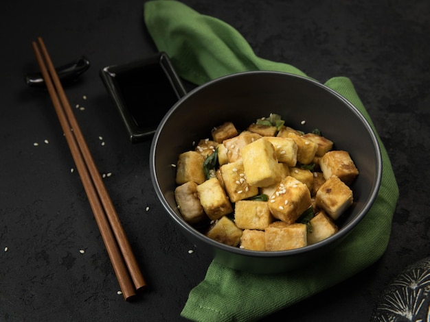 Foto banner de tofu frito con productos de soja sobre fondo negro y servilleta verde proteína alternativa vegana